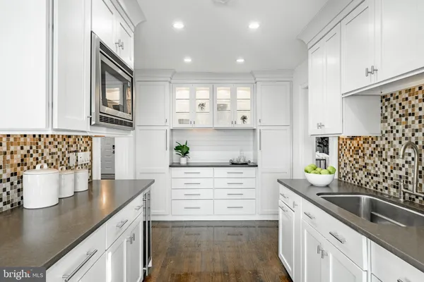 a kitchen with stainless steel appliances granite countertop a stove top oven a refrigerator a sink and white cabinets with wooden floor