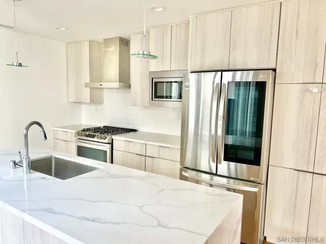 a kitchen with stainless steel appliances granite countertop a refrigerator a stove and a sink with wooden floor