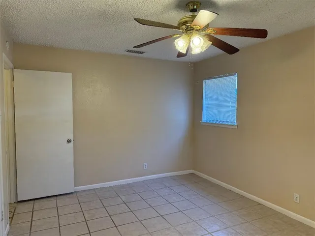 a view of an empty room and chandelier fan