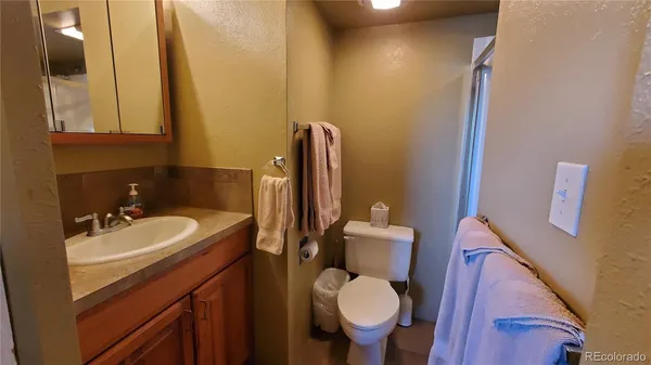 a bathroom with a toilet sink vanity granite and mirror