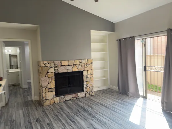 a view of an empty room with wooden floor fireplace and a window