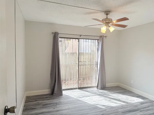 an empty room with wooden floor fan and windows