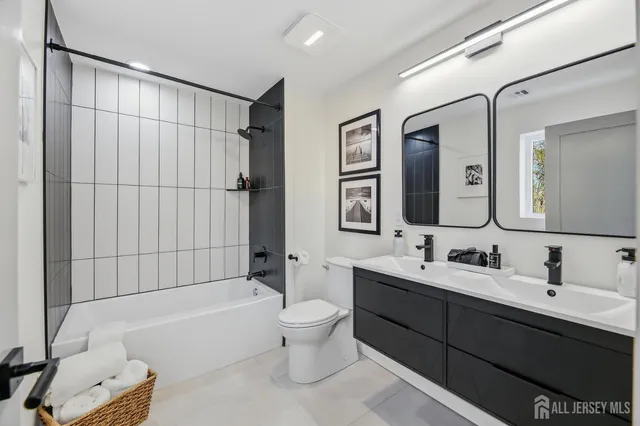 a bathroom with a double vanity sink toilet mirror and bathtub
