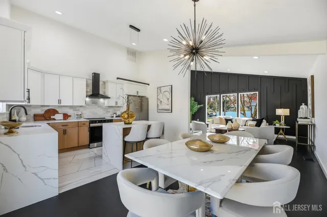 a kitchen with stainless steel appliances granite countertop a stove a sink a refrigerator dining table and chairs