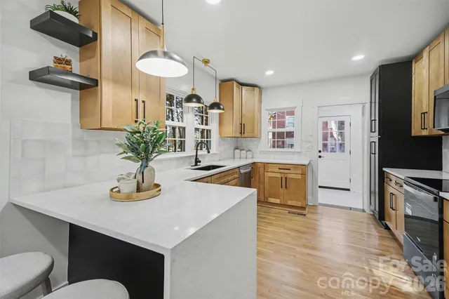 a kitchen with stainless steel appliances granite countertop a sink a stove and a wooden floors
