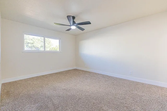 an empty room with a window and ceiling fan