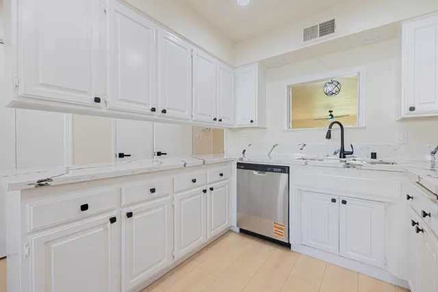 a kitchen with white cabinets and sink