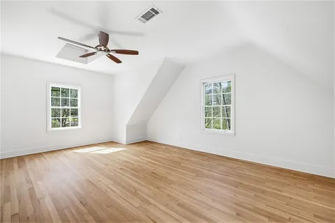 an empty room with wooden floor fan and windows