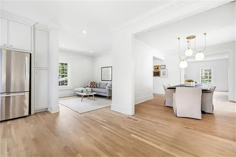 a living room with couches and kitchen view with wooden floor