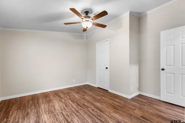 an empty room with wooden floor and a ceiling fan