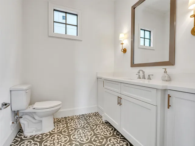 a large kitchen with stainless steel appliances kitchen island granite countertop a stove a sink a refrigerator and white cabinets with wooden floor