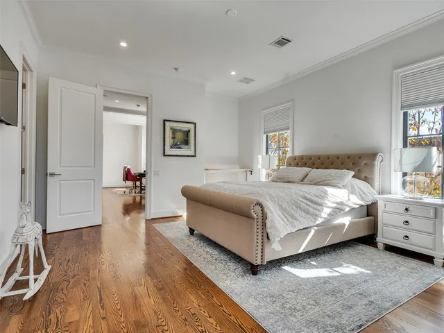 a spacious bedroom with a bed and a flat tv screen on wall