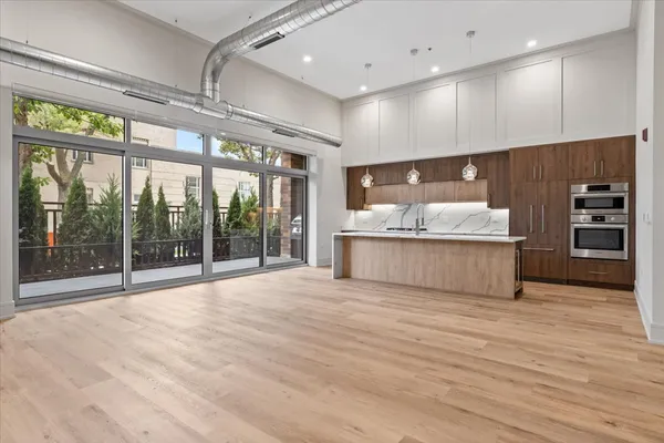 a view of an empty room with kitchen view and a large window