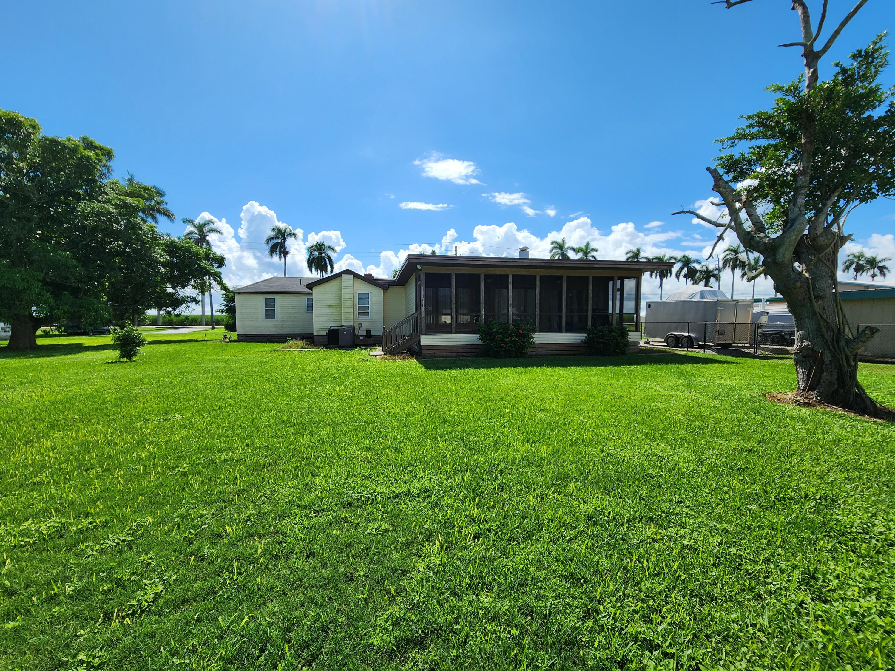 2727 Bacom Point Road Pahokee, FL 33476 - Photo 13 of 34 a view of a house with a big yard and large trees