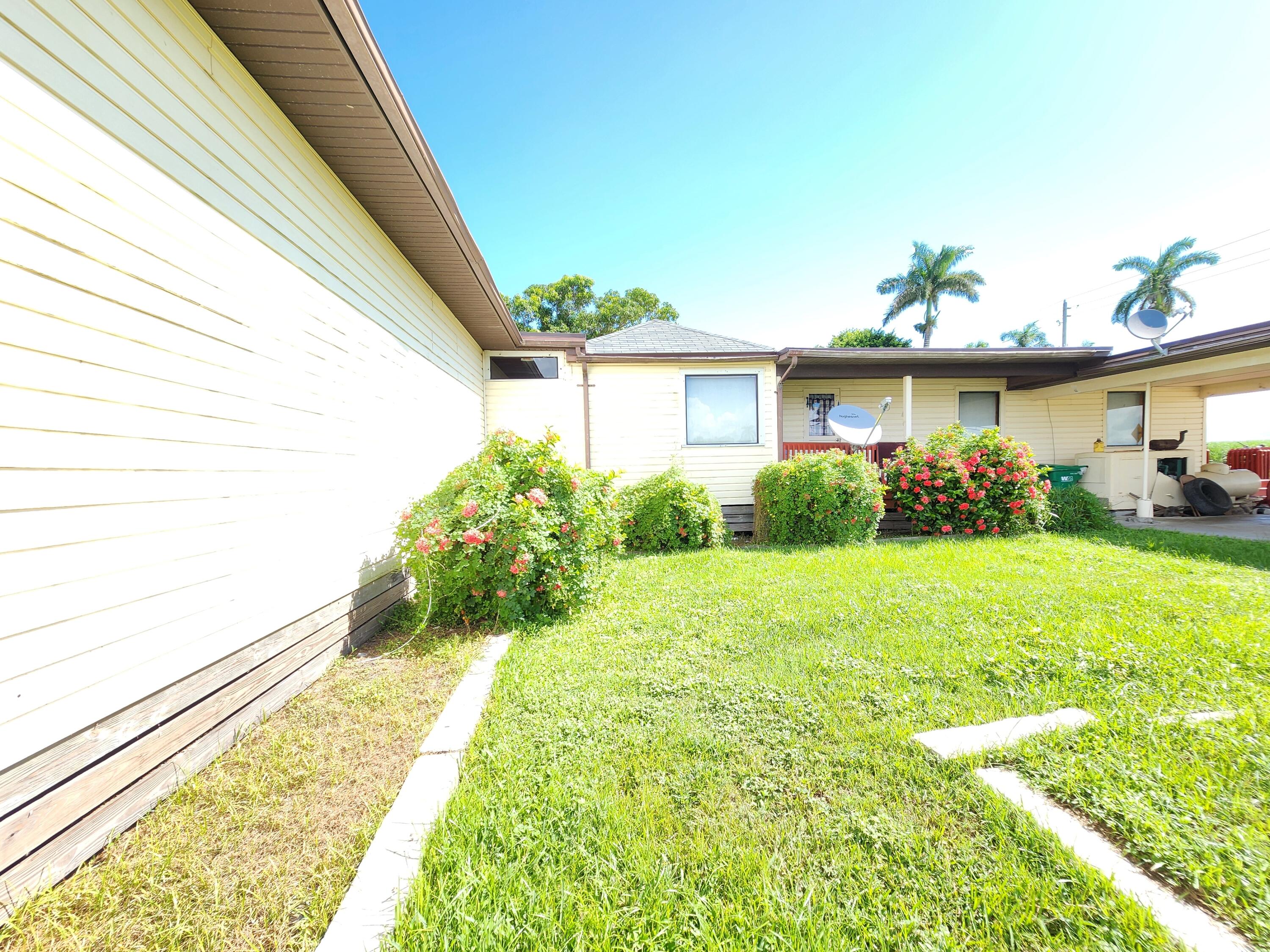 2727 Bacom Point Road Pahokee, FL 33476 - Photo 7 of 34 a front view of a house with garden