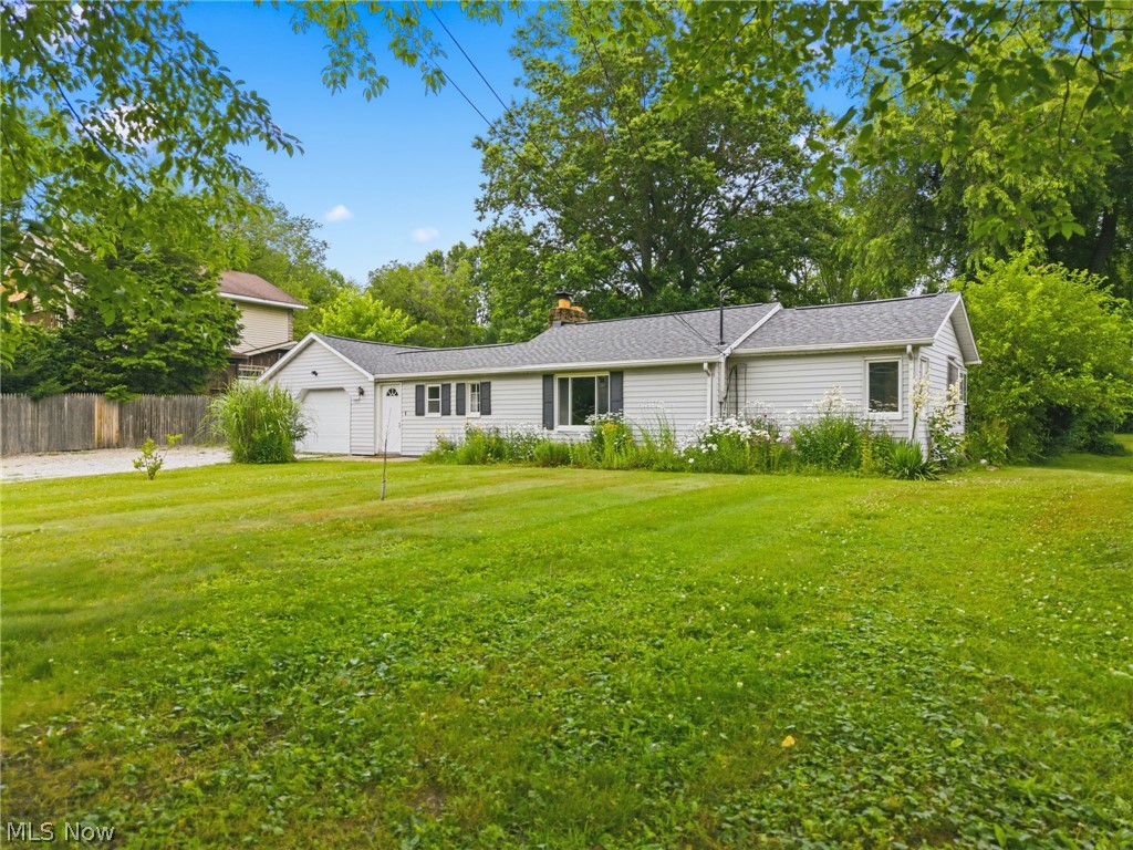 4449 18th Street Northwest Canton, OH 44708 - Photo 2 of 25 Ranch-style residence featuring light-colored siding, a dark-shingled roof, an attached garage, and a expansive grassy front yard