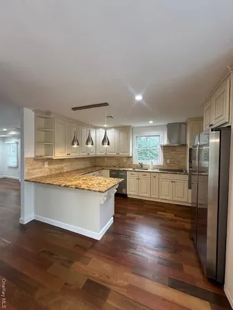 a view of a kitchen with kitchen island stainless steel appliances wooden floor and counter space