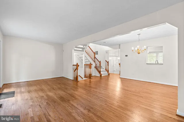a view of an empty room with wooden floor and stairs