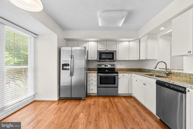 a kitchen with kitchen island granite countertop a sink cabinets and stainless steel appliances