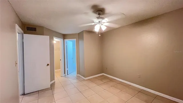 an empty room with windows and fan