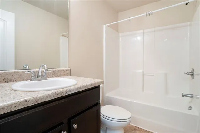 a bathroom with a granite countertop sink a toilet a mirror a bathtub and shower