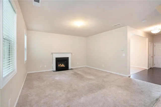 an empty room with windows and fireplace