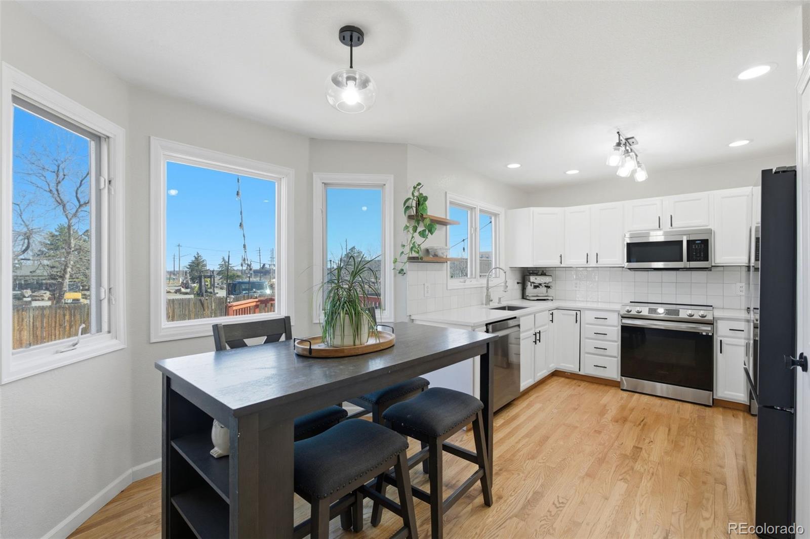 4418 Fig Street Golden, CO 80403 - Photo 8 of 50 a kitchen with stainless steel appliances granite countertop a stove top oven a sink dishwasher a dining table and chairs with wooden floor