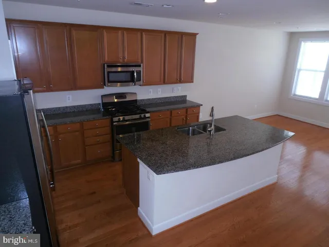 a kitchen with granite countertop a sink a stove and a microwave