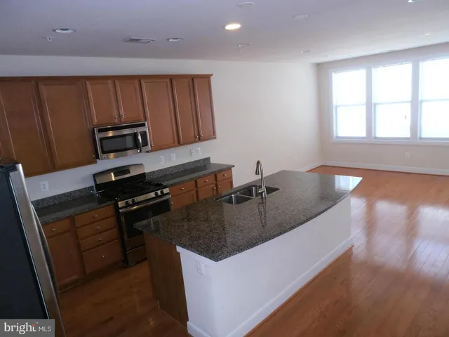 a kitchen with granite countertop a sink a stove and a refrigerator