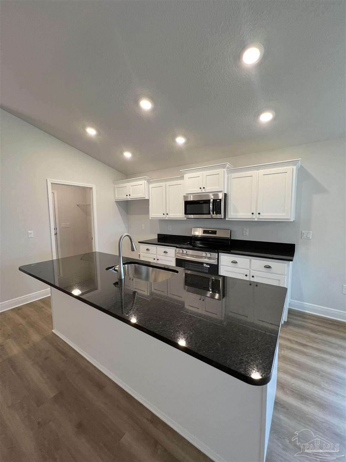 924 Rustling Pnes Road, Unit 17B Cantonment, FL 32533 - Photo 3 of 12 a kitchen with stainless steel appliances granite countertop a sink a microwave a stove and white cabinets