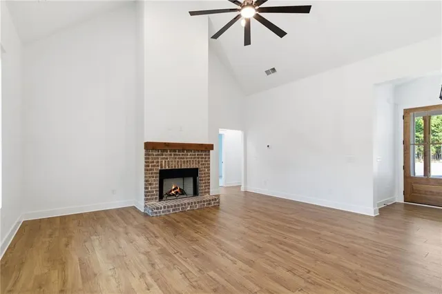 an empty room with wooden floor fireplace and windows