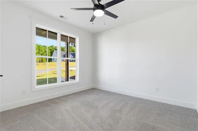 an empty room with windows and fan