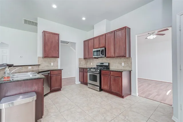 a large kitchen with stainless steel appliances granite countertop a stove sink and microwave