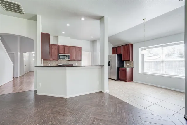 a view of kitchen with kitchen island granite countertop a stove a refrigerator a sink and a counter top space