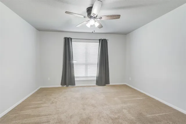 an empty room with a chandelier fan and windows