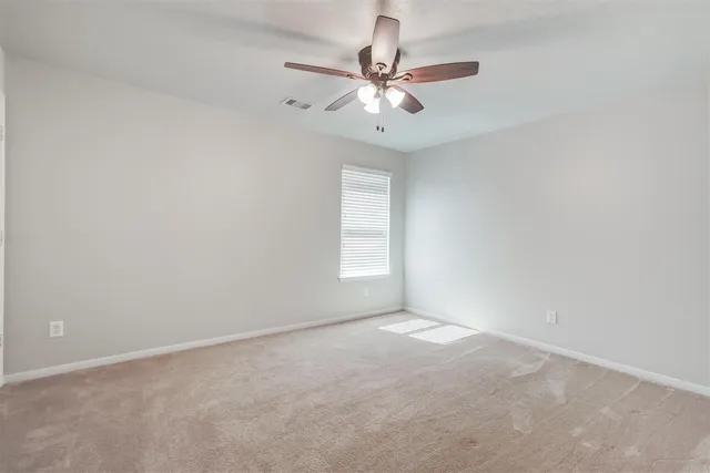 an empty room with a window and a fan