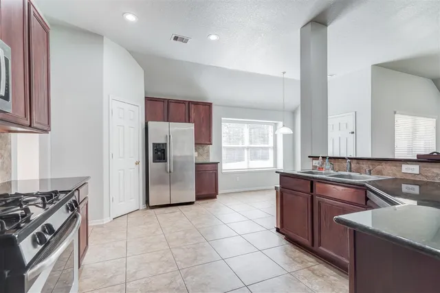 a kitchen with stainless steel appliances granite countertop a stove a sink dishwasher and a refrigerator