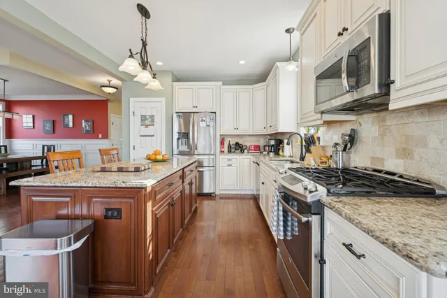 a kitchen with stainless steel appliances granite countertop a stove top oven a sink dishwasher and cabinets with wooden floor