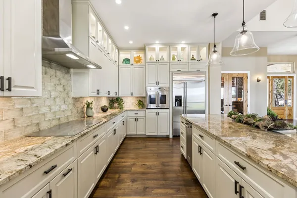 a large kitchen with stainless steel appliances lots of counter space and wooden floor