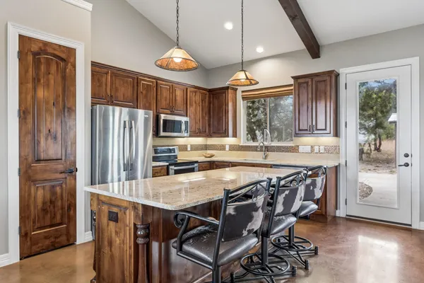 a kitchen with stainless steel appliances granite countertop a stove a refrigerator and wooden cabinets