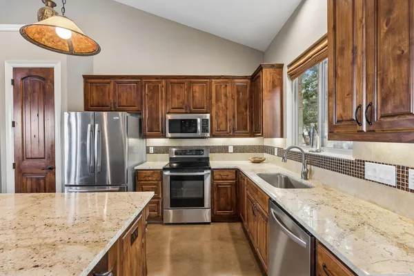 a kitchen with stainless steel appliances granite countertop a sink a stove and a refrigerator