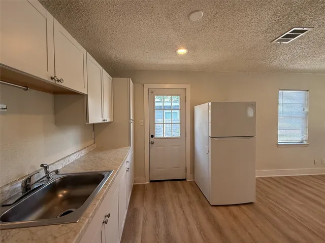a kitchen that has a sink and a stove with wooden floor