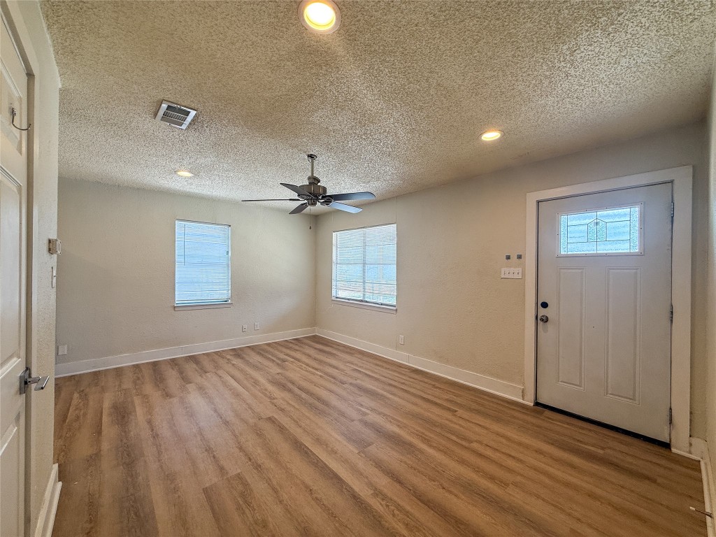 1412 Vargas Road, Unit A Austin, TX 78741 - Photo 23 of 32 an empty room with wooden floor chandelier fan and windows