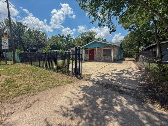 a backyard of a house with large trees and a wooden fence