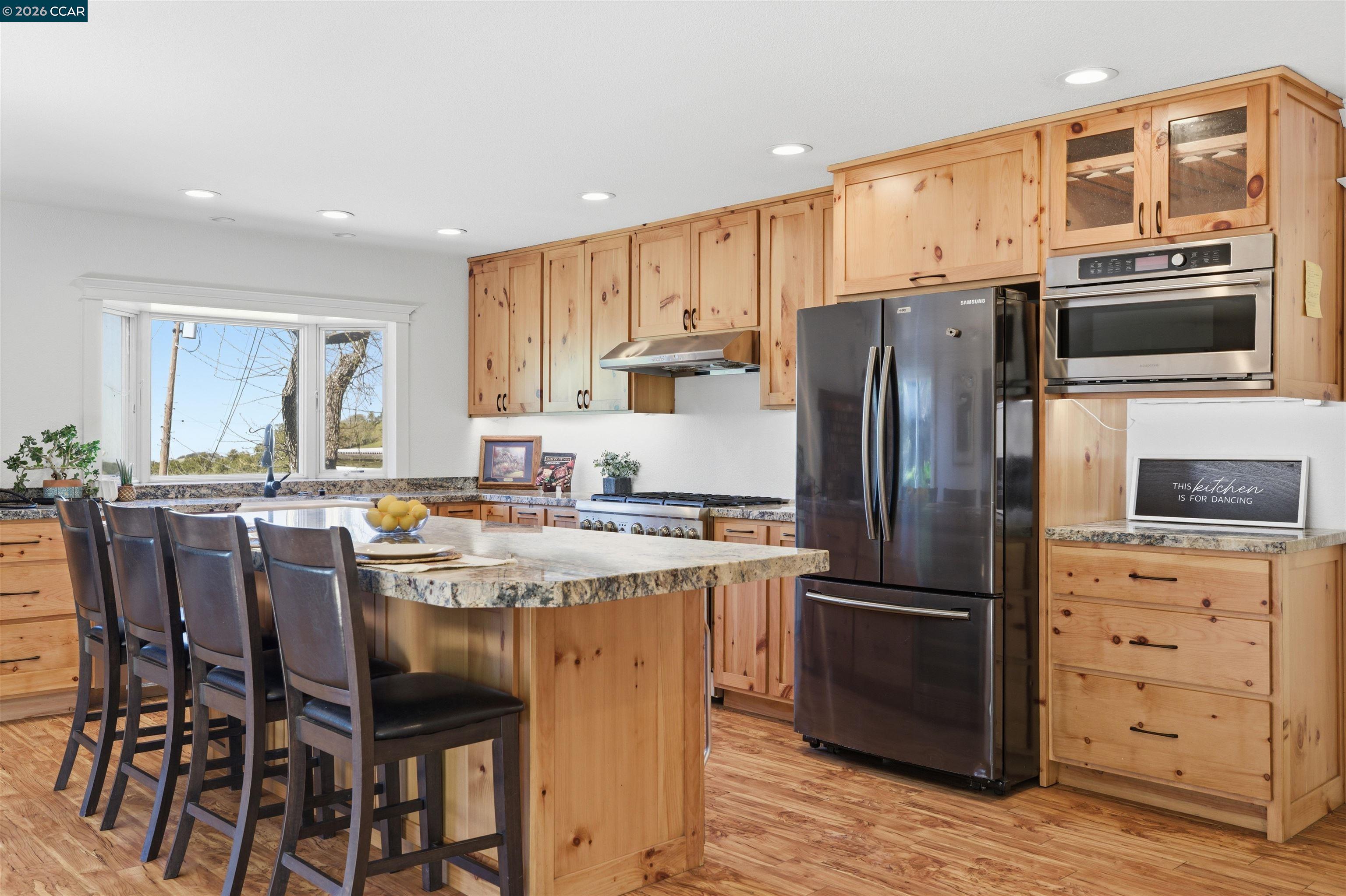 9530 Morgan Territory Road Livermore, CA 94551 - Photo 11 of 55 a kitchen with a refrigerator a stove a sink and a dining table with wooden floor
