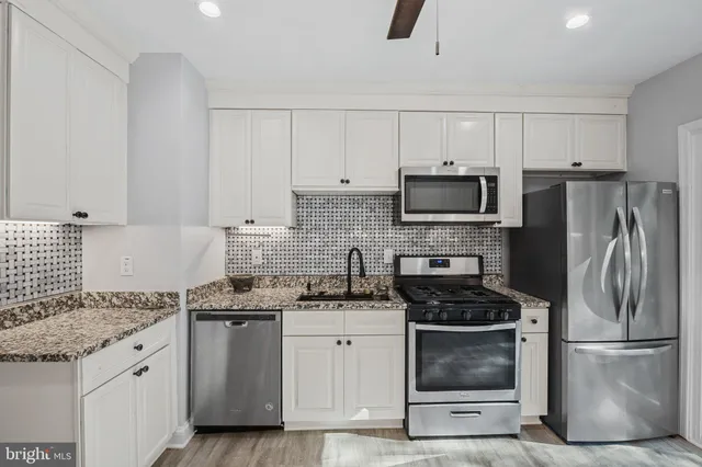a kitchen with granite countertop a refrigerator stove and microwave