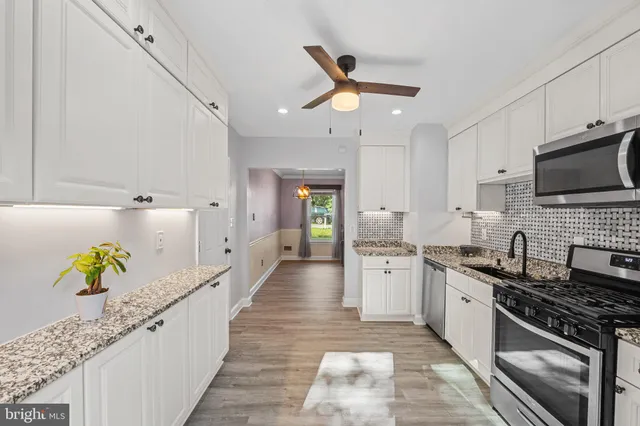 a large kitchen with stainless steel appliances granite countertop a lot of counter space and wooden floor