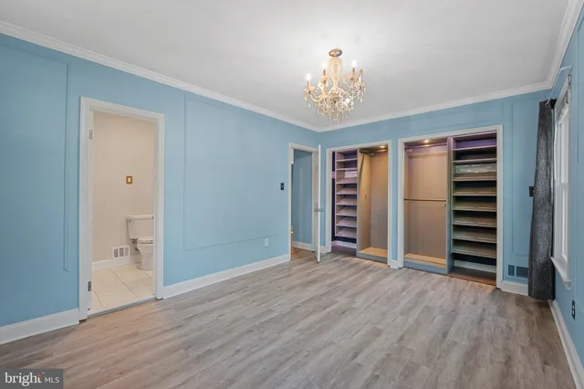 an empty room with wooden floor chandelier and windows