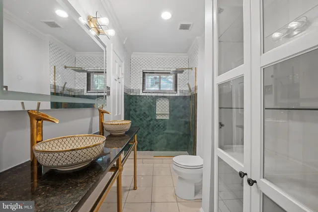 a bathroom with a granite countertop sink a toilet a mirror and shower