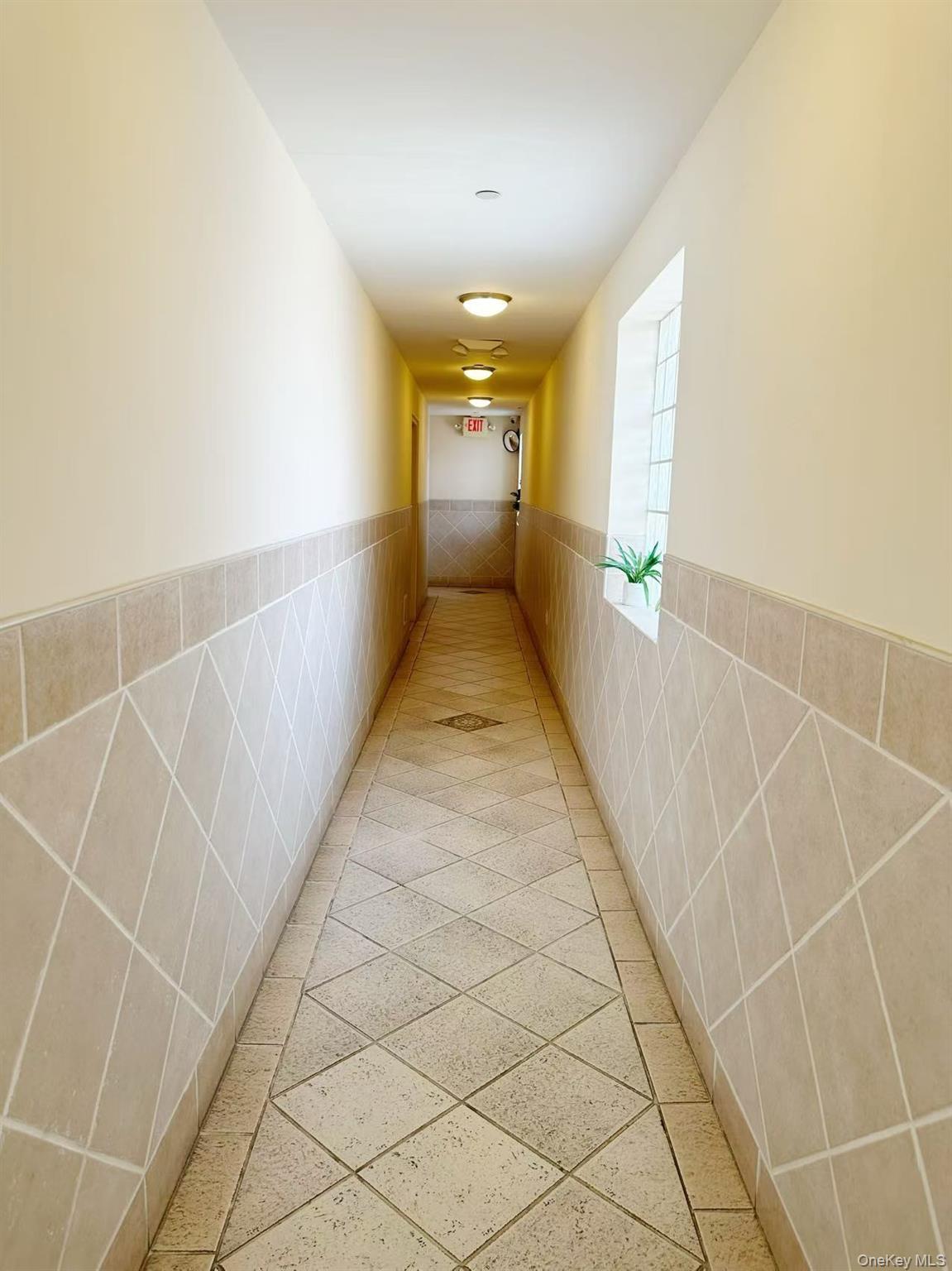 46-06 88th Street, Unit 5B Queens, NY 11373 - Photo 4 of 11 Corridor featuring tile walls and a wainscoted wall